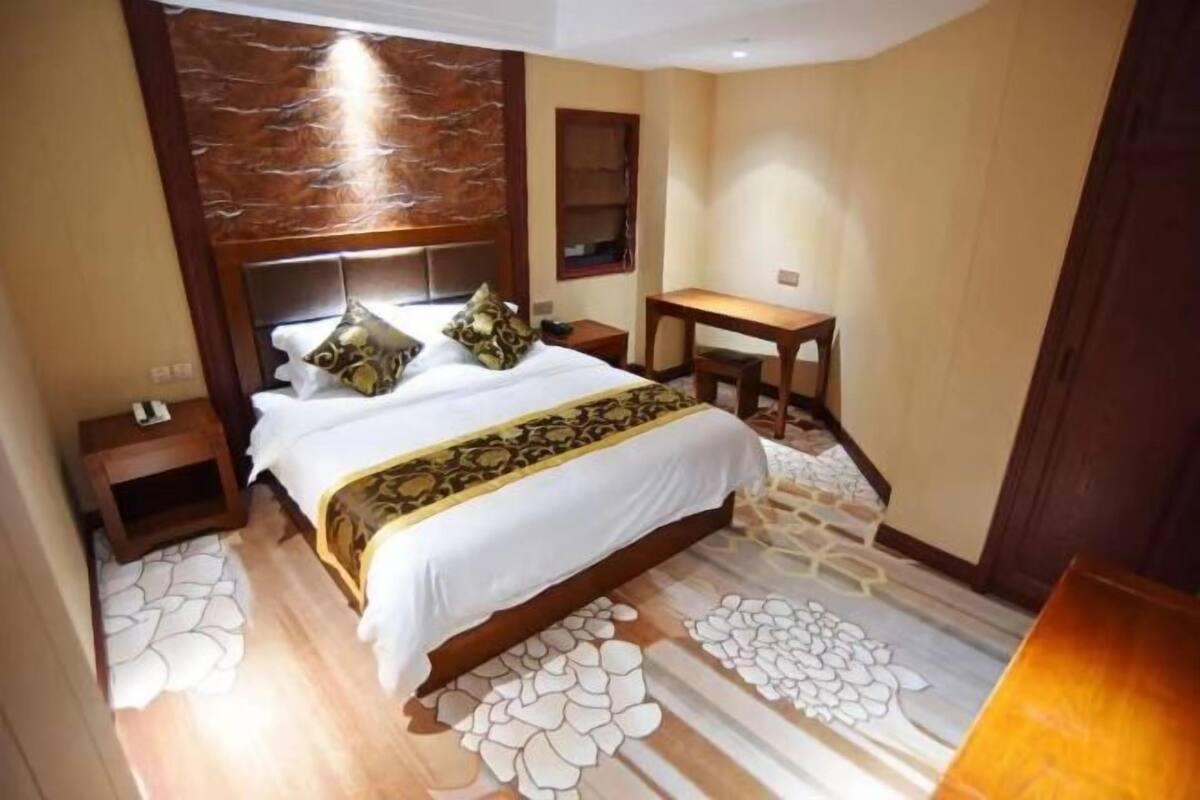 A hotel room with a large bed, a desk, and a small seating area.