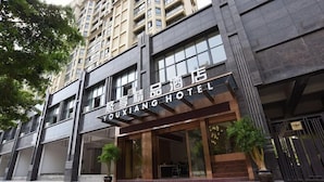 L’entrée d’un hôtel, avec une façade moderne, de grandes fenêtres et un escalier bien visible menant à l’entrée.