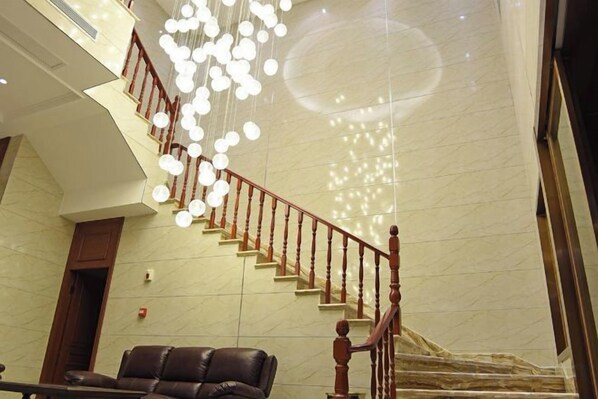 A staircase with a wooden handrail and a chandelier with multiple light fixtures. - Youxiang Hotel (Wenzhou)