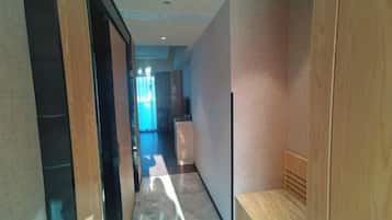 A hallway with a wooden bench, a door, and a view into a room with a window.