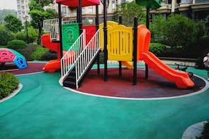 A playground with multiple slides and climbing structures, surrounded by greenery. - Youxiang Hotel (Wenzhou)
