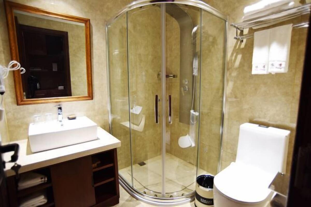 A bathroom with a glass-enclosed shower, a white sink, and a toilet.