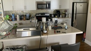 A kitchen with white cabinets, stainless steel appliances, and a tiled backsplash.