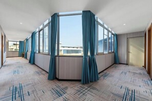 A hotel room with a large window, a corner view, and a patterned carpet. - Tianlong Boutique Hotel (Ji'an County)