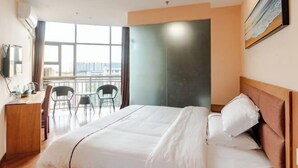A hotel room with a bed, a desk, and chairs near a large window. - Tianlong Boutique Hotel (Ji'an County)