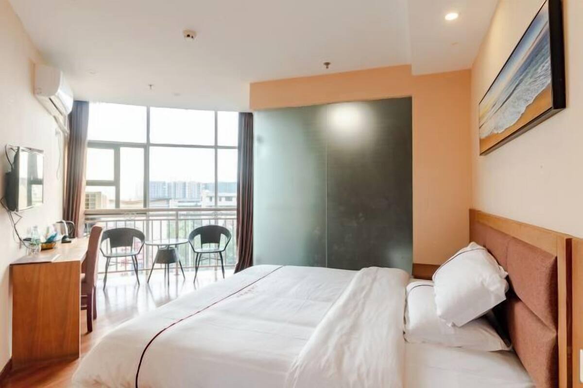 Een hotelkamer met een bed, een bureau en stoelen bij een groot raam.
