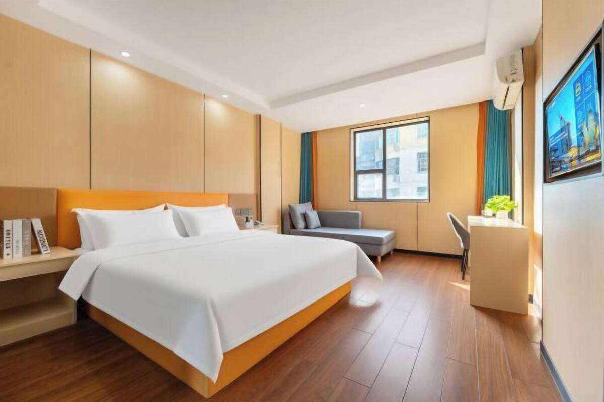 Een moderne hotelkamer met een groot bed, een bureau, een bank en een raam met gordijnen.