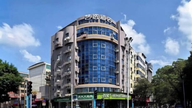 A multi-story hotel with a curved facade, multiple balconies, and various signage indicating different businesses on the ground floor. - Tianlong Boutique Hotel (Ji'an County)