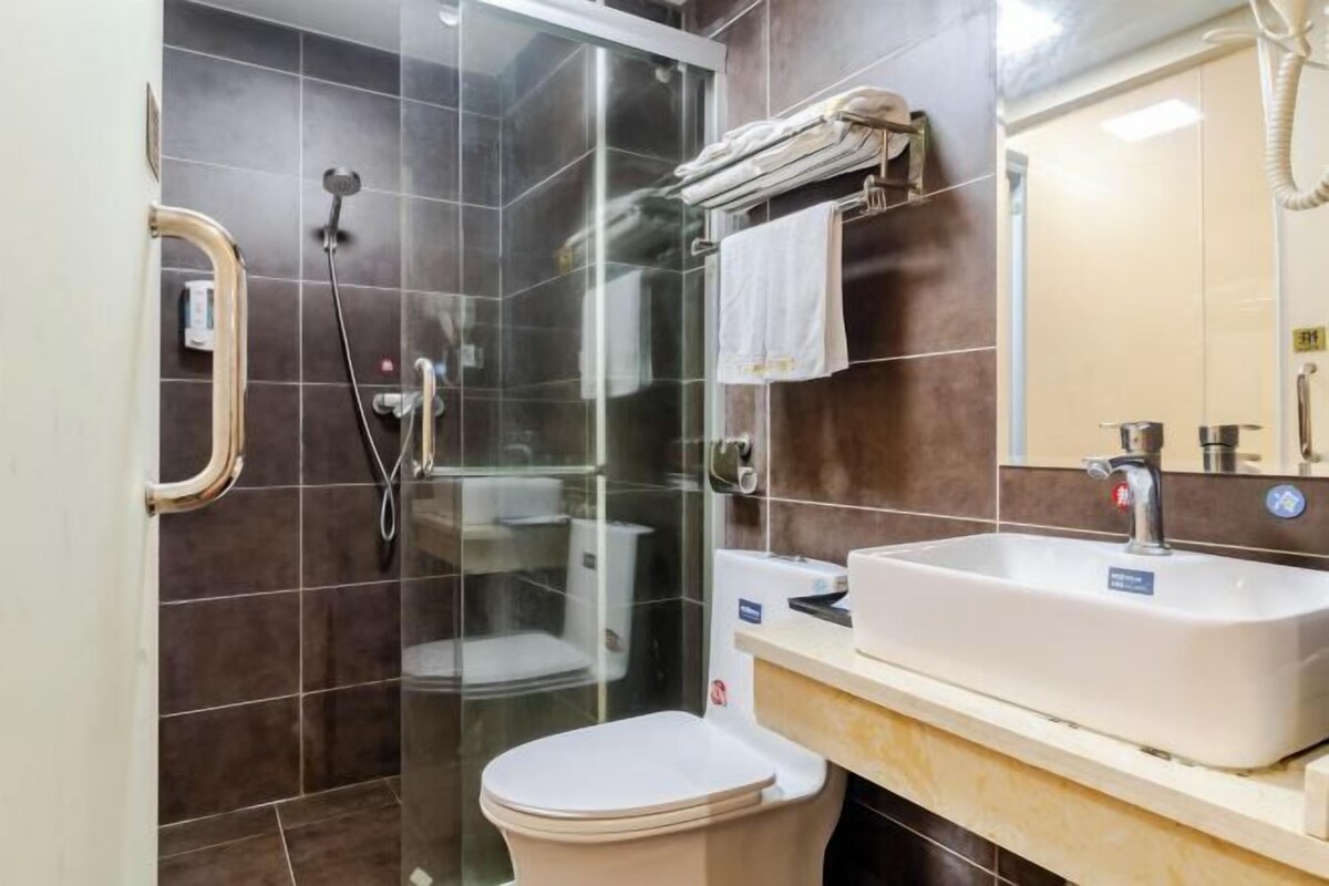 Un baño moderno con ducha de vidrio, inodoro blanco y lavamanos con espejo.