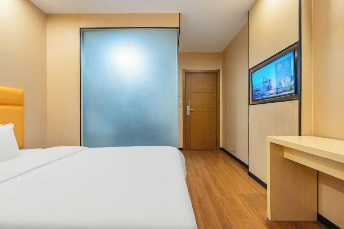 Een hotelkamer met een bed, een bureau, een televisie en een deur.