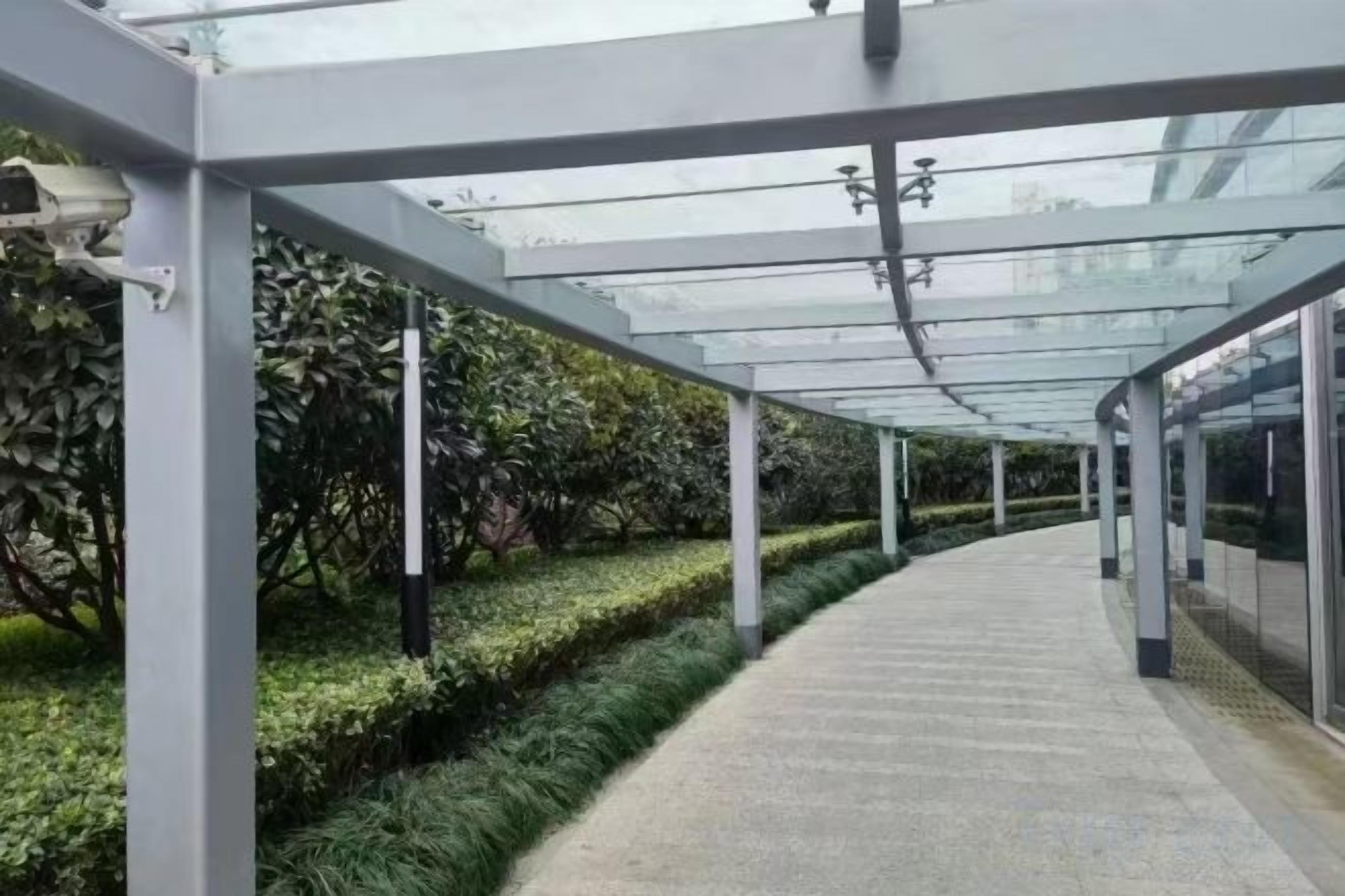 Un paseo techado con techo de cristal, rodeado de follaje.