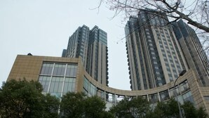 A high-rise building with a curved glass facade, surrounded by trees. - Riyueguang Apartment Hotel (Shanghai)