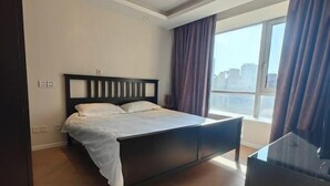 A modern hotel room with a large bed, a desk, and a view of the city. - Riyueguang Apartment Hotel (Shanghai)