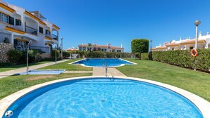 A swimming pool surrounded by well-maintained grass and a clear blue sky. - Casa Encantada - Communal pool & garden, just a 5 minute walk to town centre (Carvoeiro)