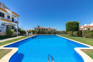 A rectangular swimming pool with a clear blue water surface, surrounded by a well-maintained lawn and a stone wall. - Casa Encantada - Communal pool & garden, just a 5 minute walk to town centre (Carvoeiro)