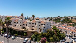 A coastal residential area with modern buildings, a parking lot, and a clear view of the sea. - Casa Encantada - Communal pool & garden, just a 5 minute walk to town centre (Carvoeiro)