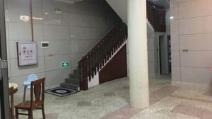 A lobby with a staircase, a wooden chair, a small table, and a sign on the wall. - Binhai Hotel, Meili Island, Putian City (Putian)