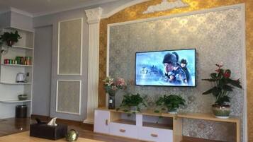 A living room with a flat-screen TV mounted on a textured wall, a wooden coffee table, and a white entertainment unit.