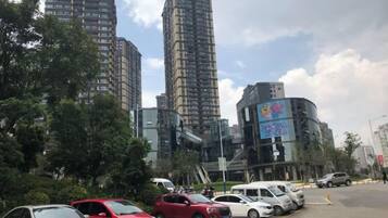 A parking lot with several cars, surrounded by tall buildings and trees.