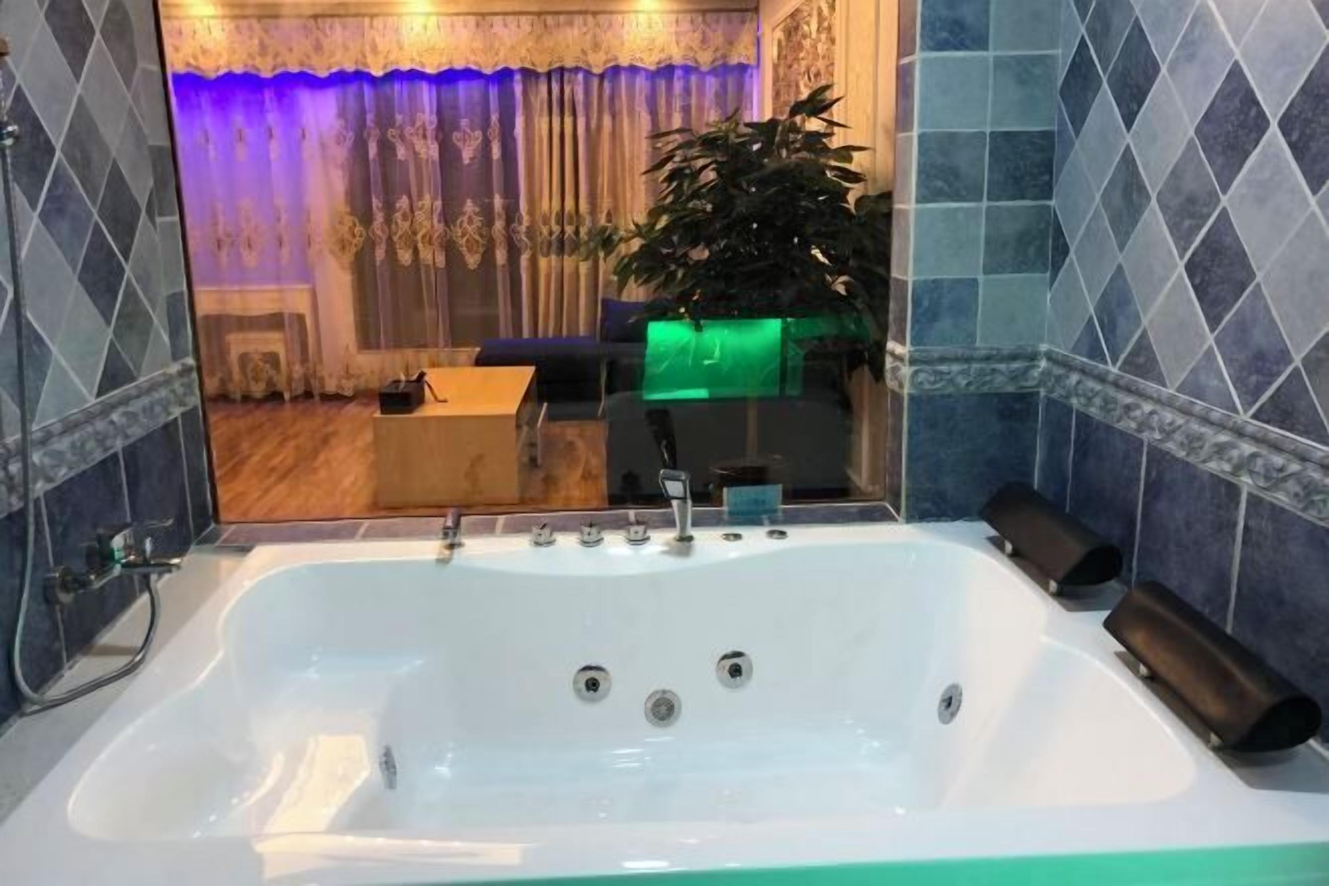 A bathroom with a large bathtub, a mirror, and a potted plant.
