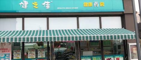 A health drug store with a green awning and multiple informational posters.
