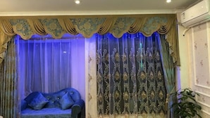 A room with a sofa, curtains, and a plant.