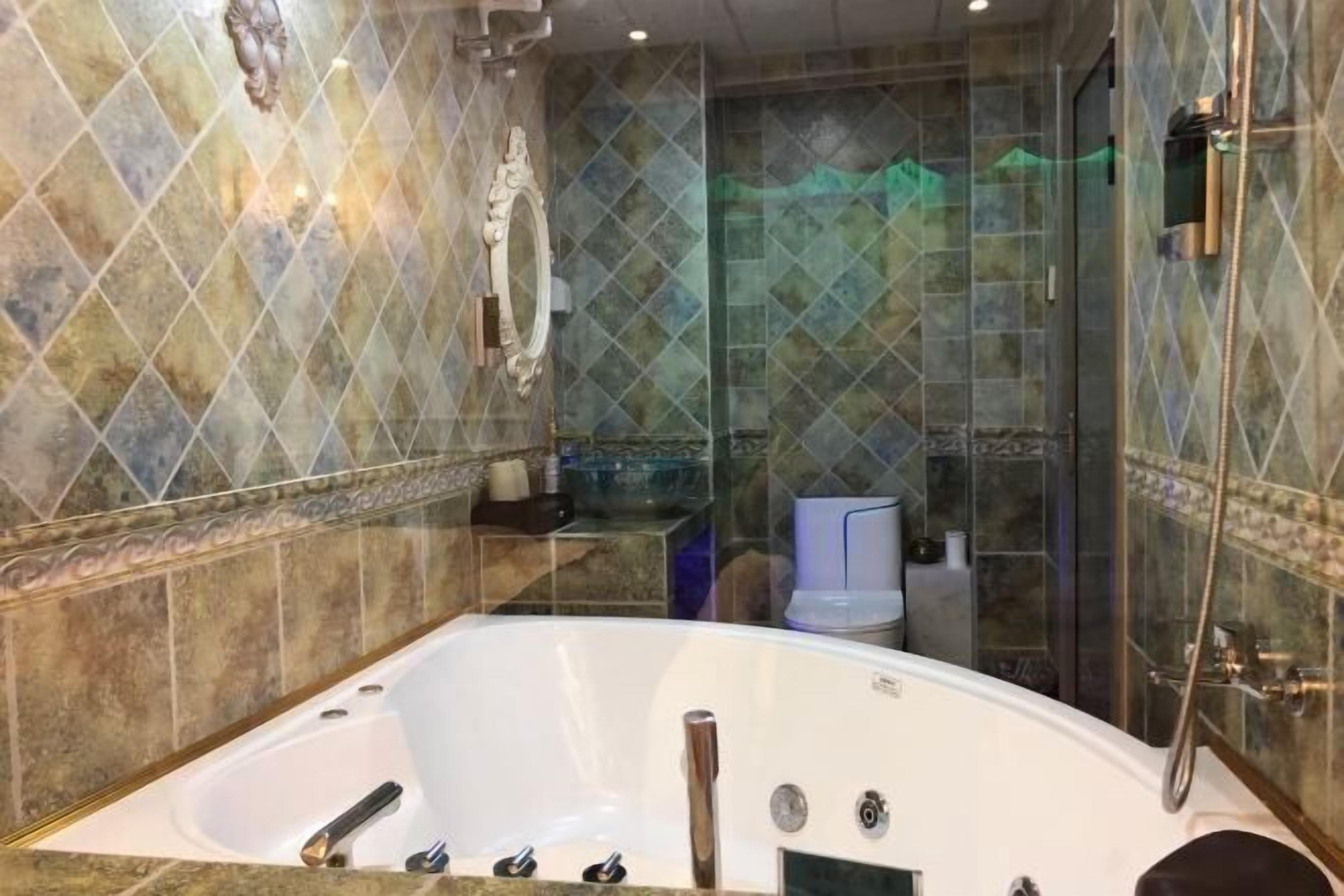 A modern bathroom with a freestanding bathtub, a glass shower enclosure, and a marble-tiled wall.