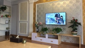 A living room with a flat-screen TV mounted on a textured wall, a wooden coffee table, and a white entertainment unit.