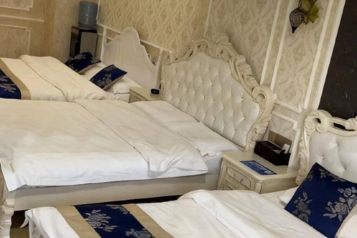 Een tweepersoonsbed met hoofdbord, nachtkastje en nachttafeltje.