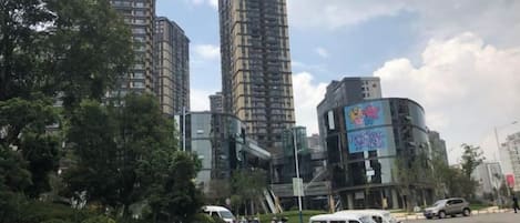 A parking lot with several cars, a building with a curved facade, and tall residential buildings in the background.