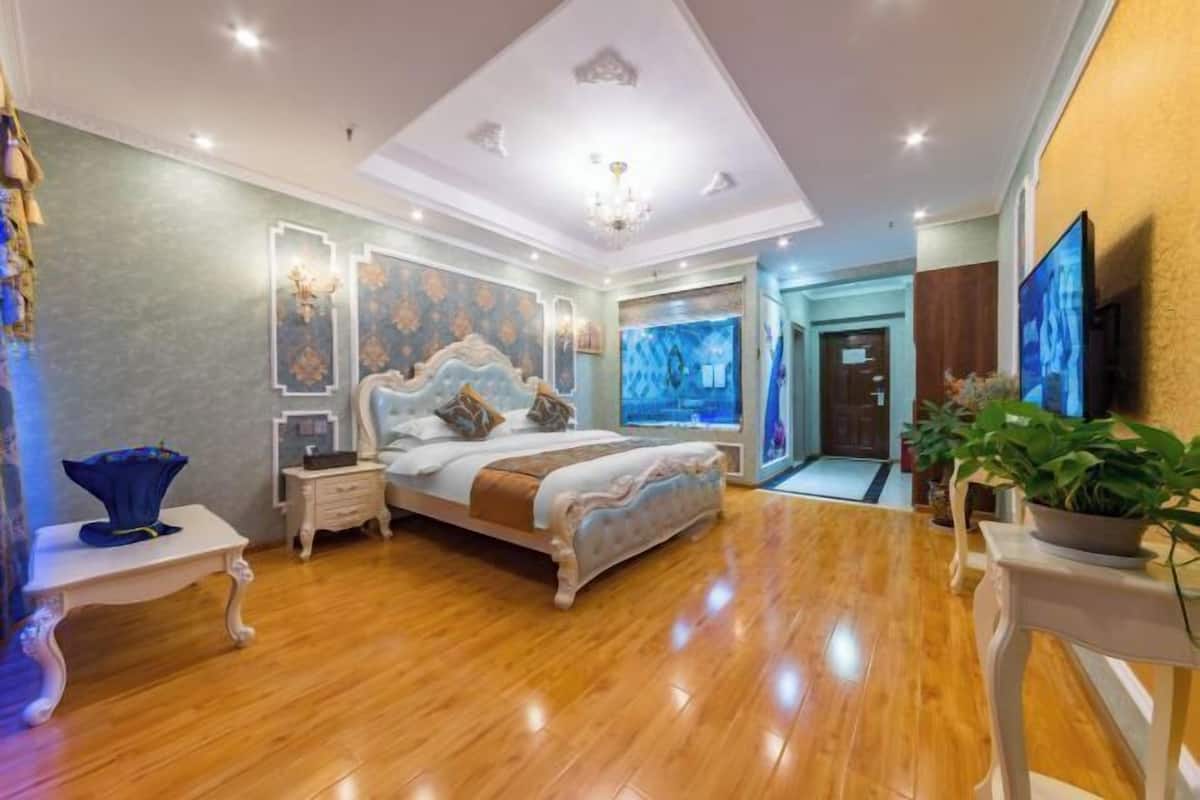 Een slaapkamer met een bed, nachtkastjes, een kroonluchter en een televisie.