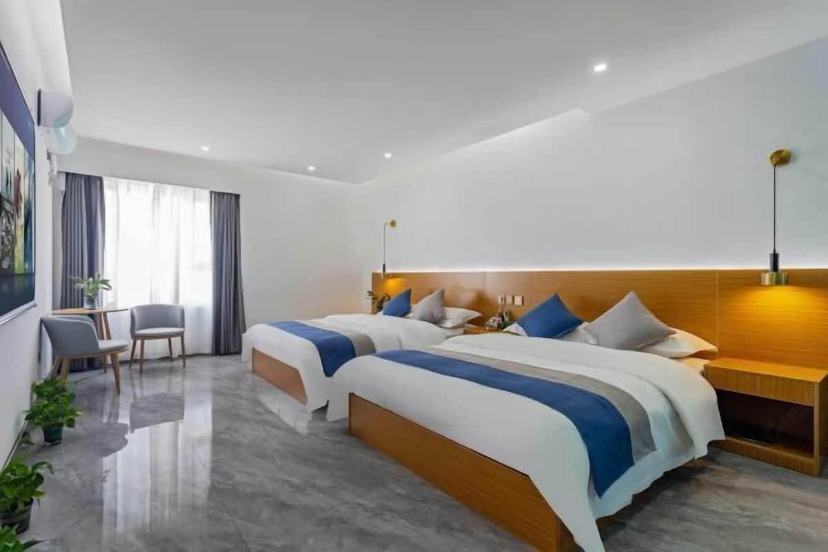 Een moderne hotelkamer met twee bedden, een bureau en een stoel.