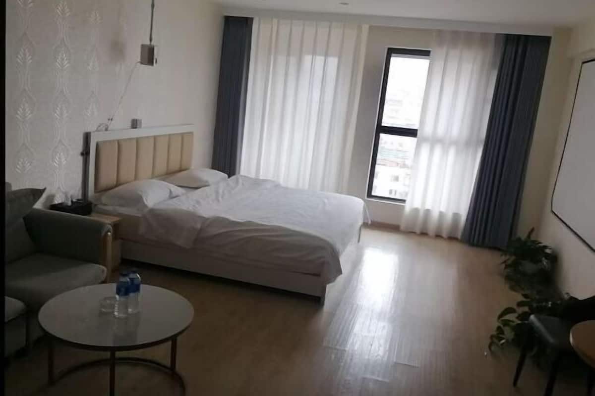 Een hotelkamer met een bed, een bank, een kleine tafel en een raam met gordijnen.