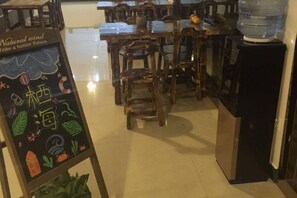 A restaurant interior with wooden tables and chairs, a chalkboard menu, and a water dispenser. - Dali Qihai Station (Dali City)