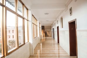 A long, narrow hallway with large windows on one side and doors on the other.