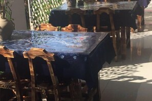 Een eethoek met tafels bedekt met blauwe tafelkleden en houten stoelen.