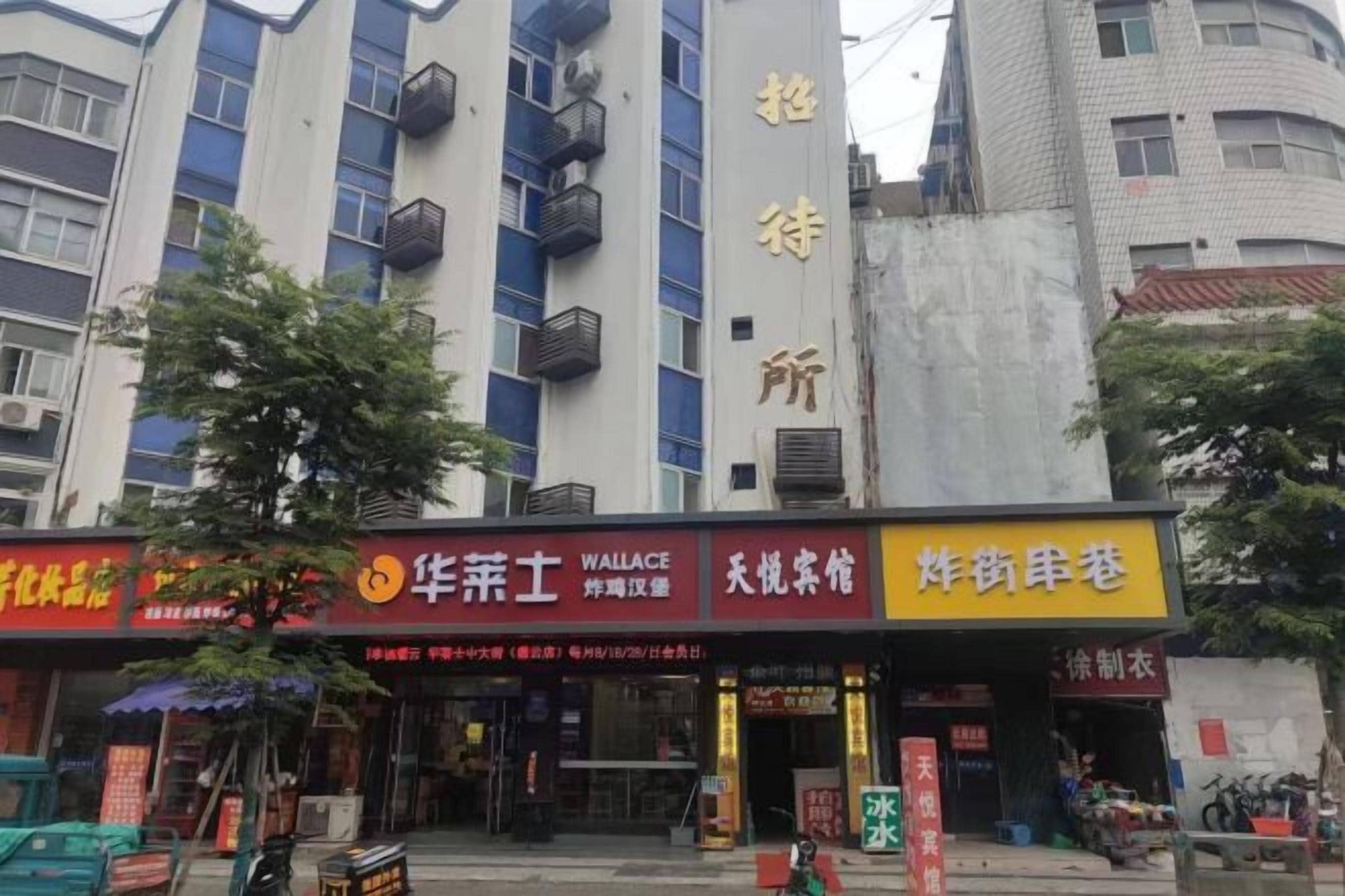 A building with multiple commercial establishments on the ground floor, including a Wallace store, a tea shop, and a clothing store.