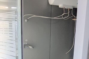 A bathroom with a grey door, a shower area, and visible plumbing. - Guanyuntianyuebingguan (Guanyun)