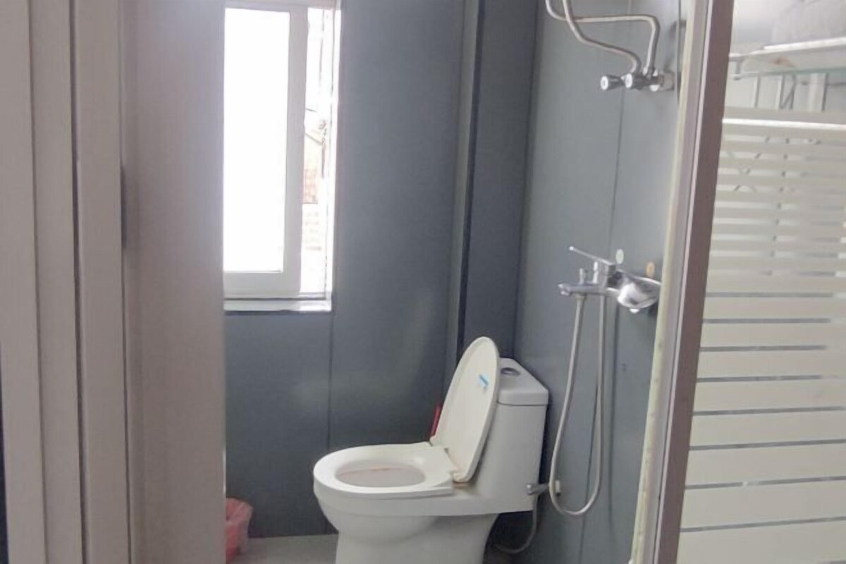 A bathroom with a toilet, a shower, and a window.