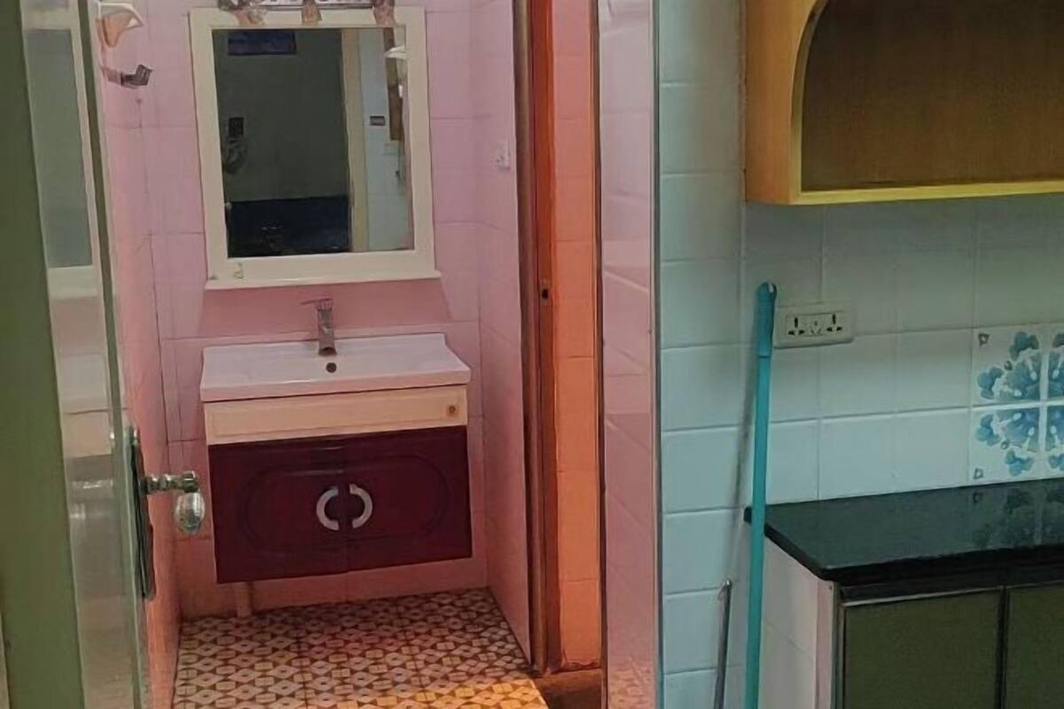 A bathroom with a pink tiled wall, a white sink, and a mirror above it.