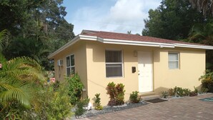 A single-story house with a red-tiled roof, beige walls, and a small front porch.