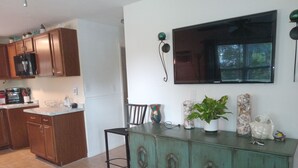 A kitchen with wooden cabinets, a dining table, and a green cabinet with decorative items.