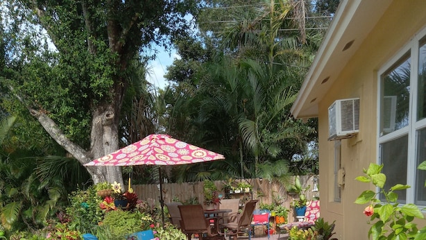 A patio area with a brick floor, outdoor furniture, and potted plants.