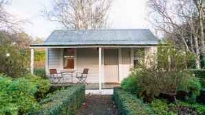 A small house with a porch, two chairs, and a table. - Tuhitarata Hideaway. Romantic Couples Retreat (Pirinoa)
