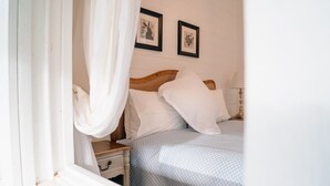 A bedroom with a wooden headboard, white bedding, a bedside table with a lamp, and two framed pictures on the wall. - Tuhitarata Hideaway. Romantic Couples Retreat (Pirinoa)