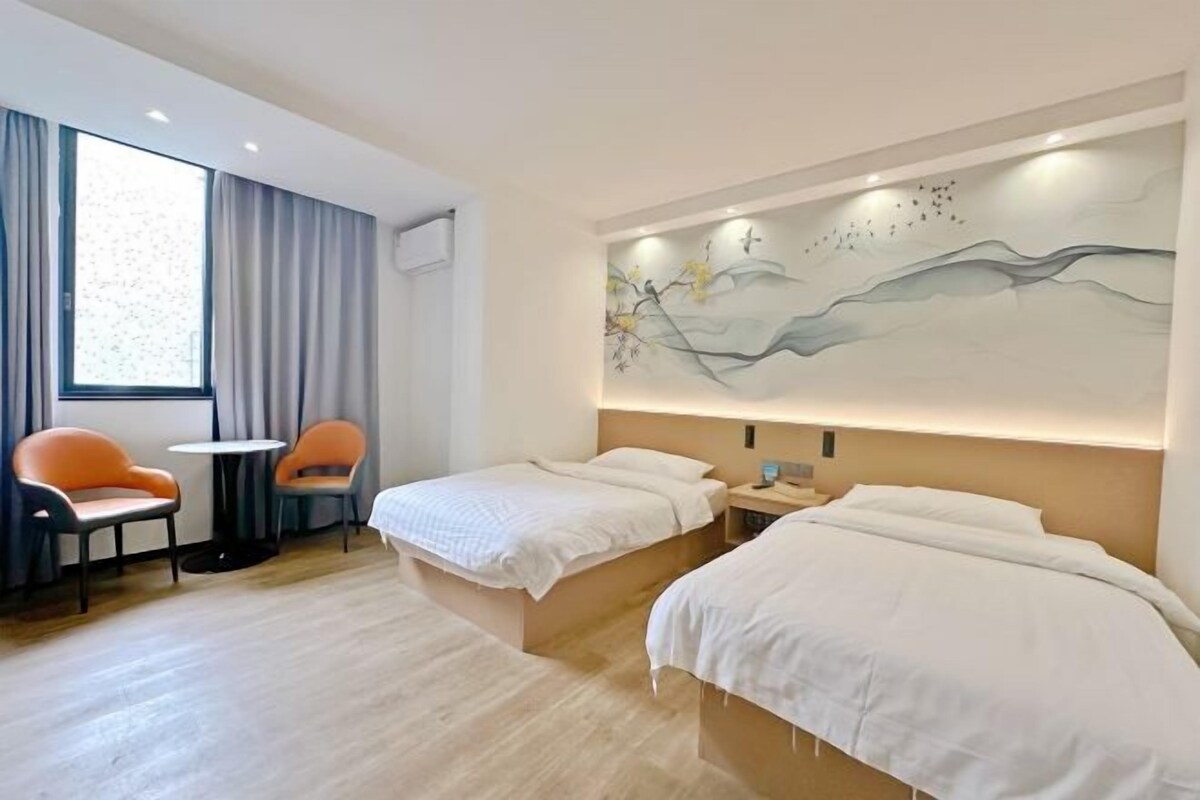 Une chambre d’hôtel avec deux lits, un bureau et une chaise.
