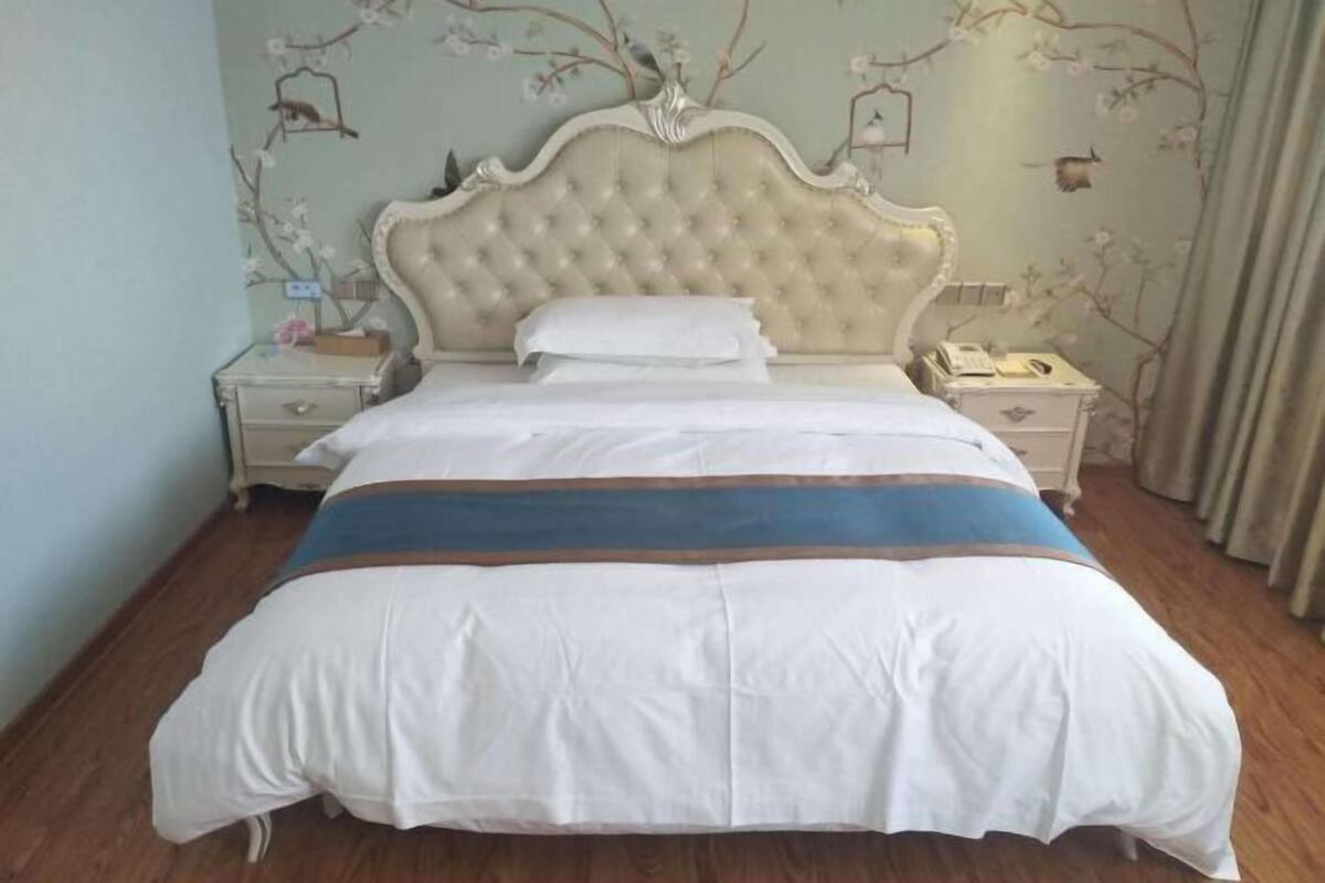 A neatly made bed with a tufted headboard, white bedding, and a blue accent.