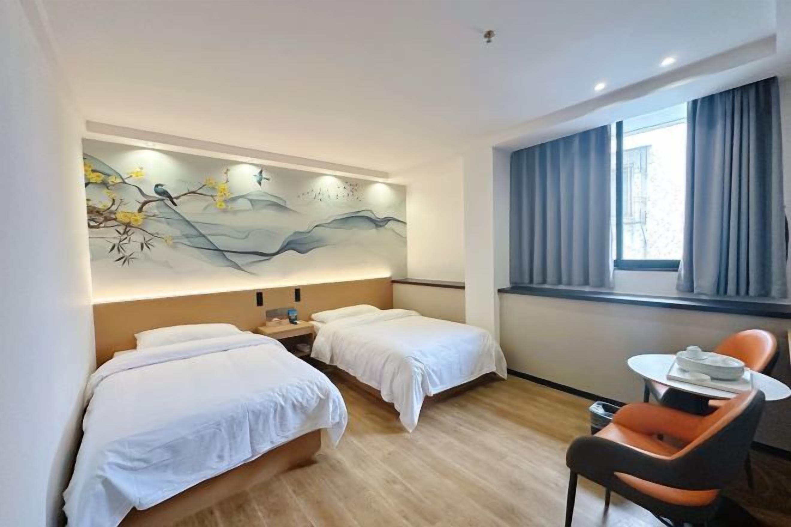 A hotel room with two beds, a small table, and a chair.