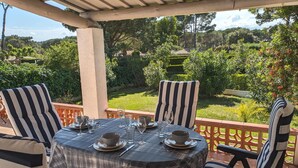 A covered outdoor dining area with a table set for four, surrounded by striped chairs. - Las flores 3A, Begur, Costa Brava (Begur)