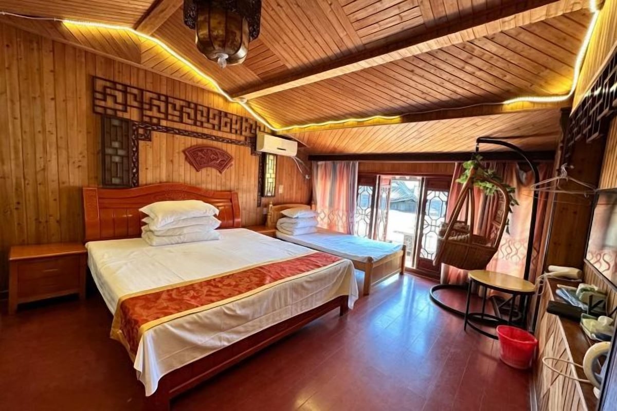 A wooden-paneled room with a large bed, a smaller bed, and a seating area.
